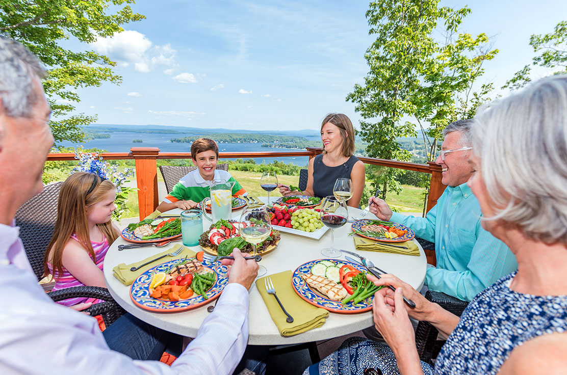family dining on patio overlooking lake